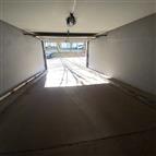 Prostorná garáž s betonovou podlahou a automatickými vraty, v dobrém stavu, ideální pro pohodlné parkování a uskladnění vozidel